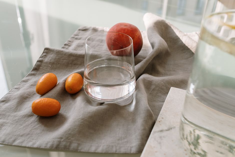Ett glas vatten bredvid färsk frukt på ett bord