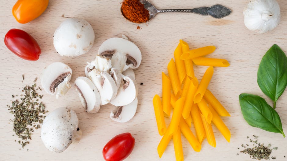 Pasta, färska champinjoner och örter arrangerade på träbakgrund