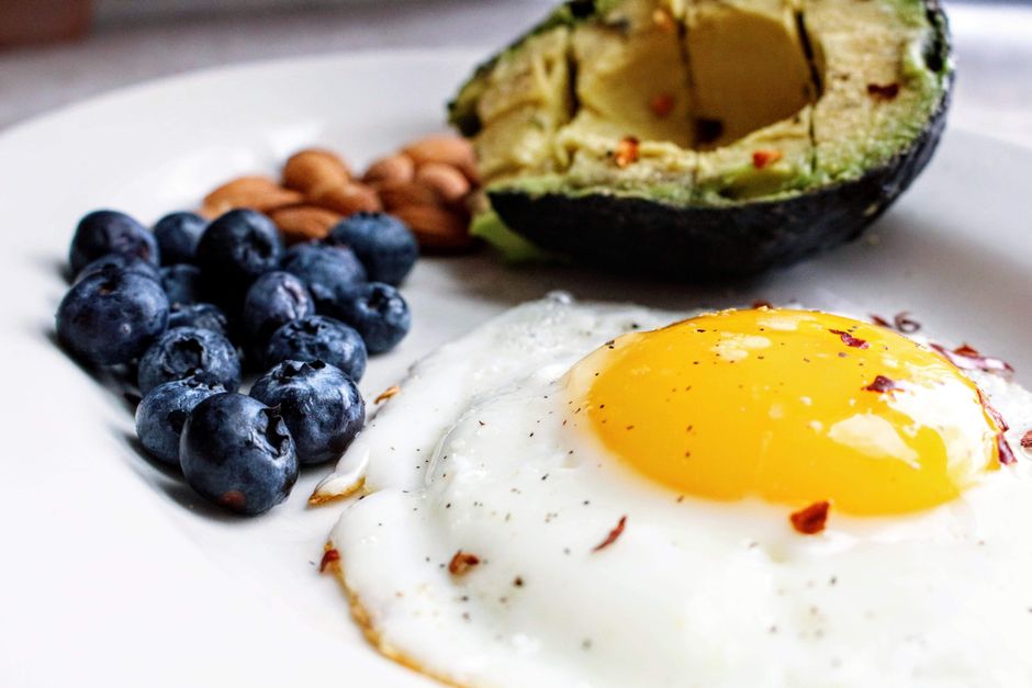 Näringsrik frukost med stekt ägg, avokado, blåbär och mandlar